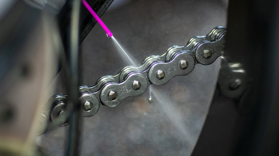 Close-up of lubricant application to a motorcycle chain