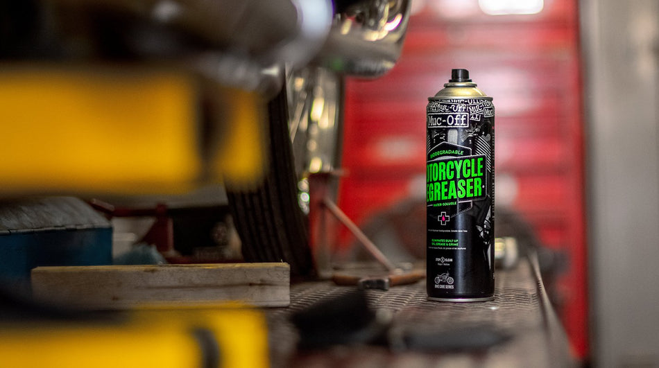 Muc-Off Motorcycle Bio Degreaser on a workshop bench beside a motorcycle