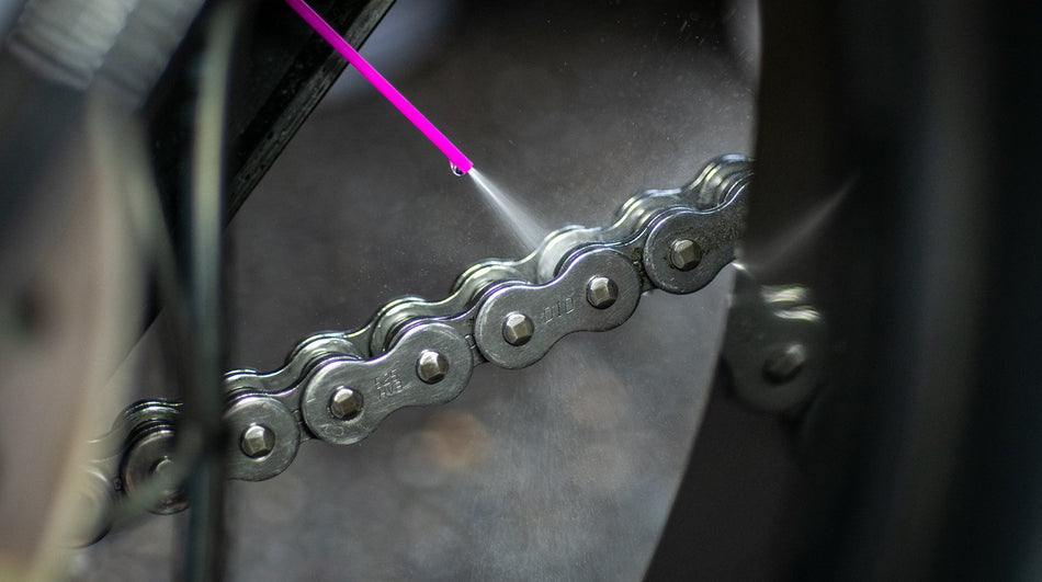 Muc-Off Dry Chain Lube being applied to a motorcycle chain, close-up